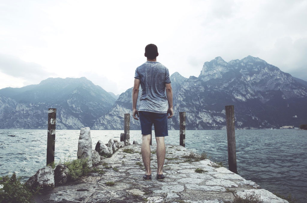 man standing on a pier overlooking water praying God will strengthen him