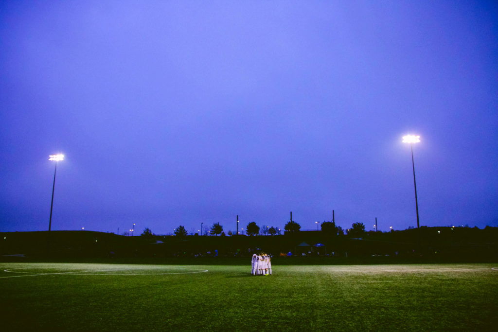 baseball leadership team huddled in a circle on a baseball field